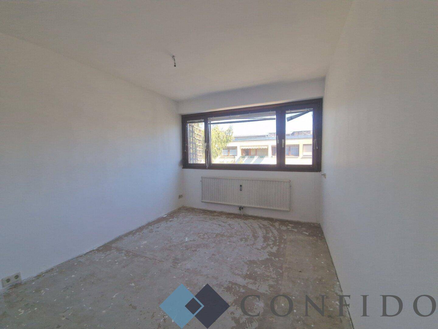 Heller, unmöblierter Raum mit Fenster, ideal als Schlafzimmer oder Arbeitszimmer nach Renovierung.