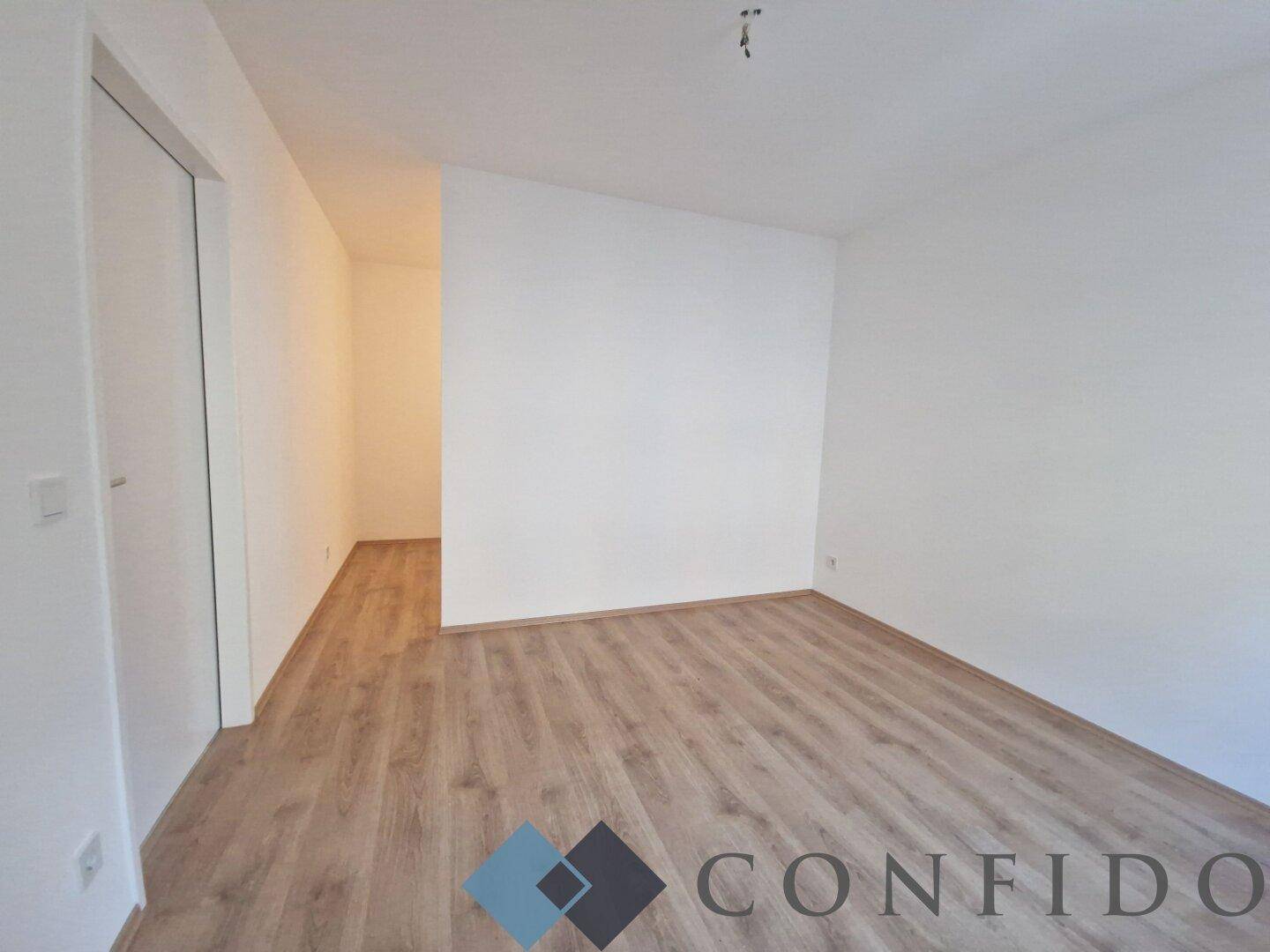 Heller Flur mit Laminatboden und weißen Wänden, verbindet die verschiedenen Wohnbereiche.