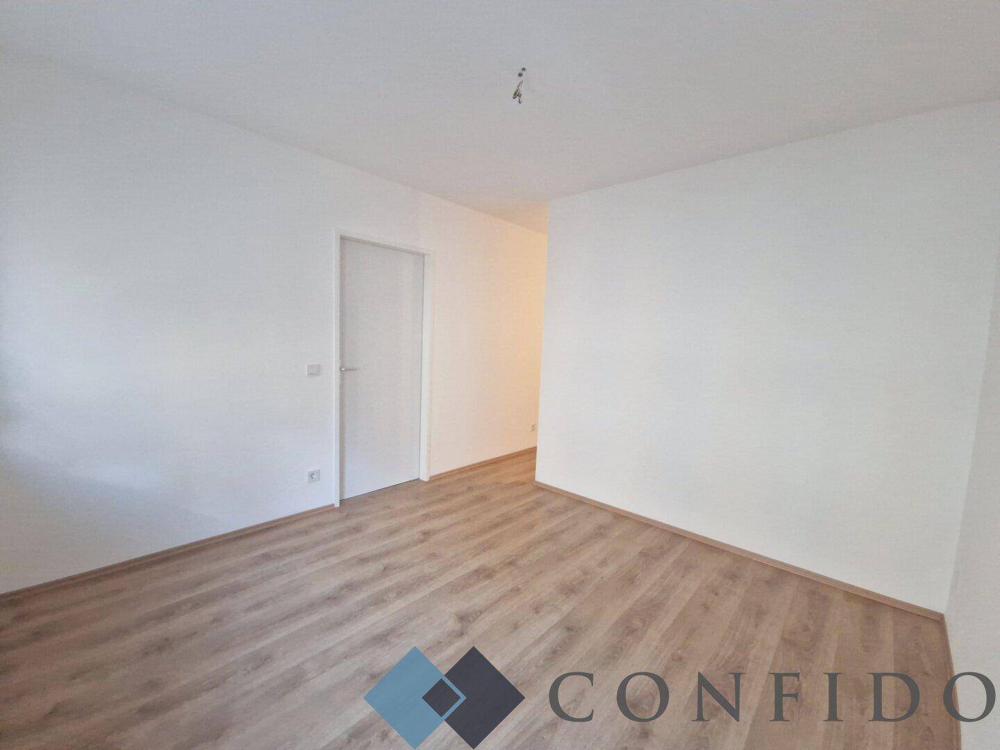Sauberer Flur mit Laminatboden und weißer Tür, bietet Zugang zu weiteren Räumen der Wohnung.