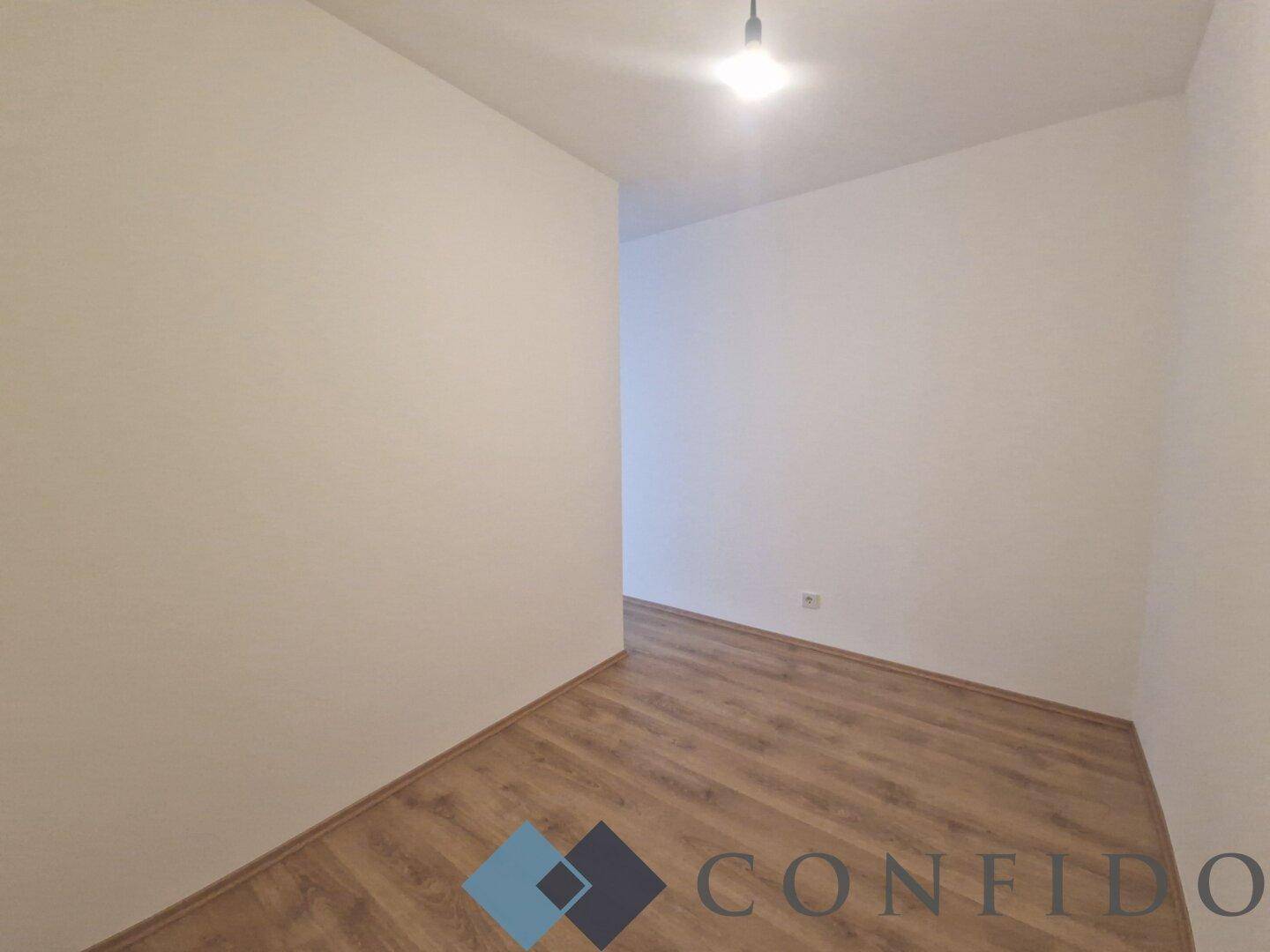 Schlichter Flur mit Laminatboden und weiß gestrichenen Wänden, gut beleuchtet durch Deckenleuchte.