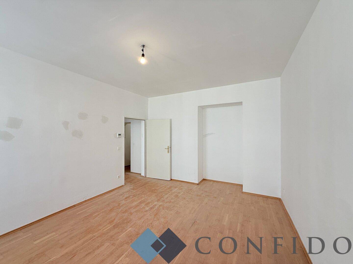 Leeres Zimmer mit Holzboden und weiß gestrichenen Wänden, bietet vielseitige Nutzungsmöglichkeiten.