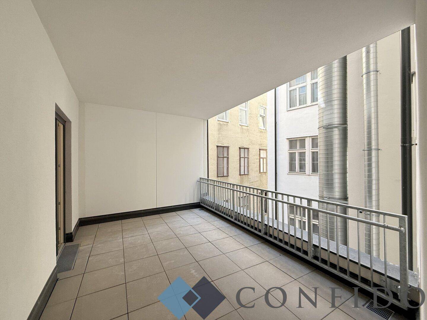 Geräumige Loggia mit Fliesenboden und Blick auf den ruhigen Innenhof, ideal zum Entspannen.