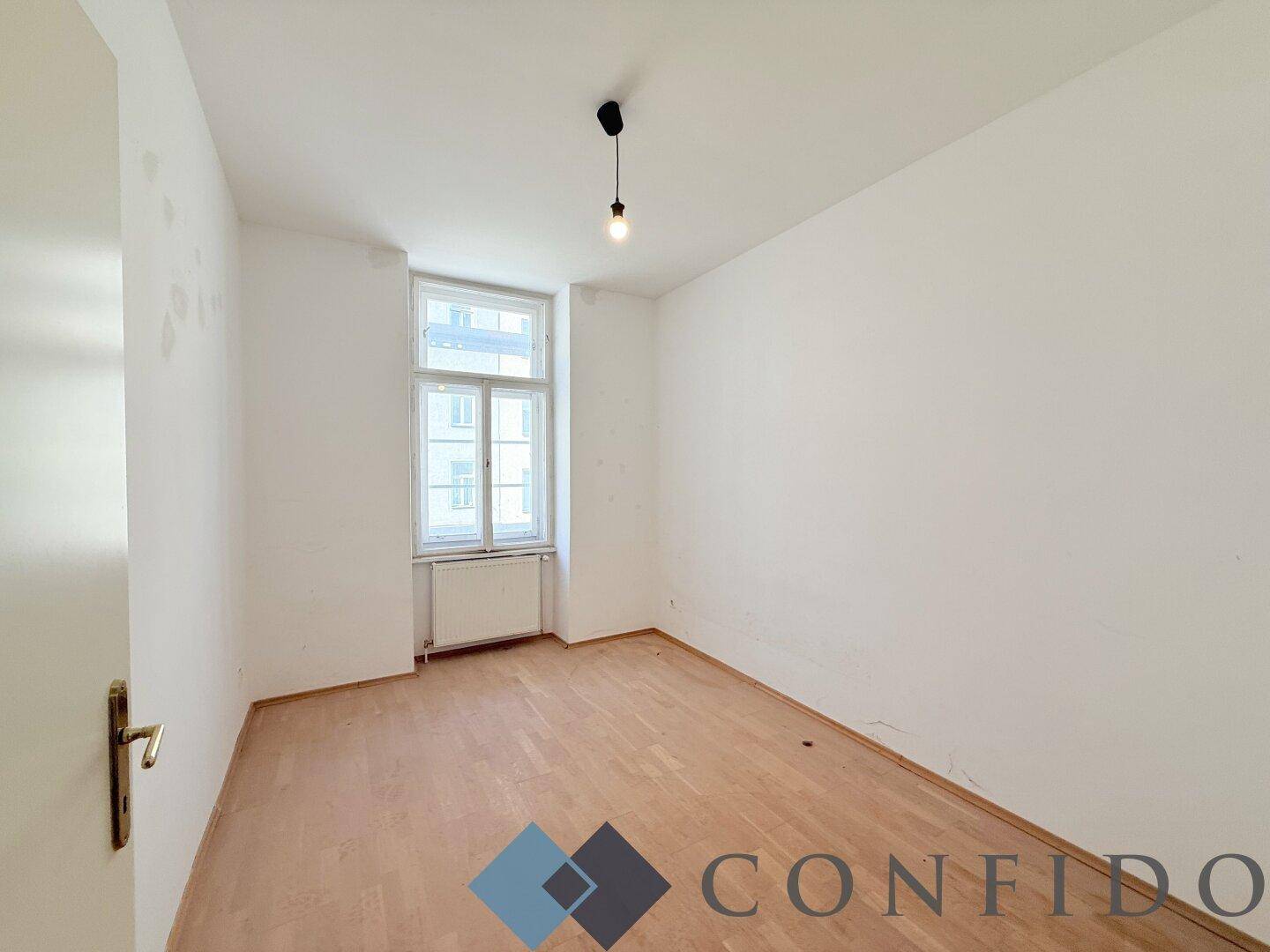 Ruhiges Schlafzimmer mit Parkettboden und großem Fenster, ideal für erholsame Nächte.