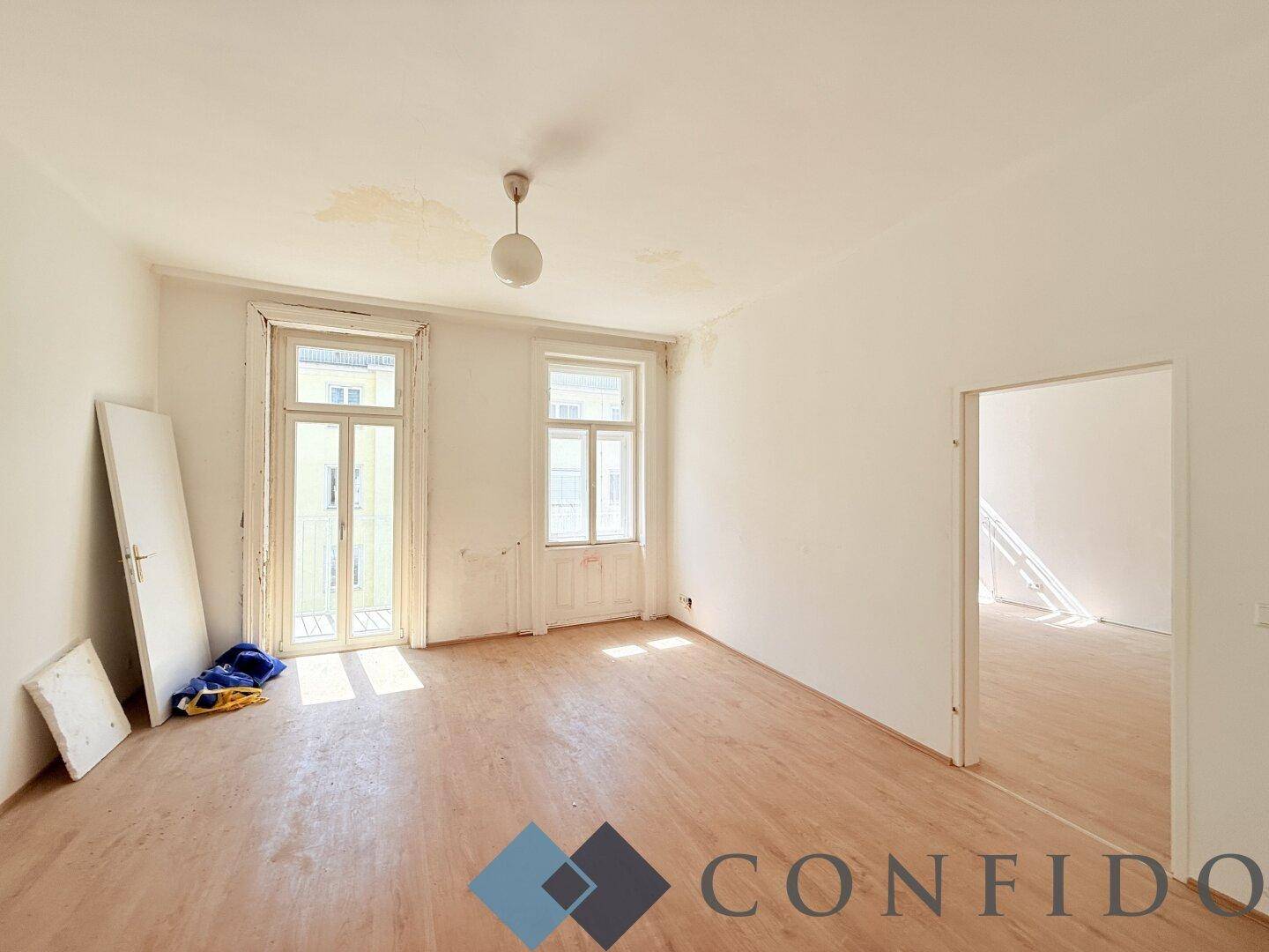 Heller, leerer Raum mit Holzboden und zwei Fenstern, bereit für die Renovierung.