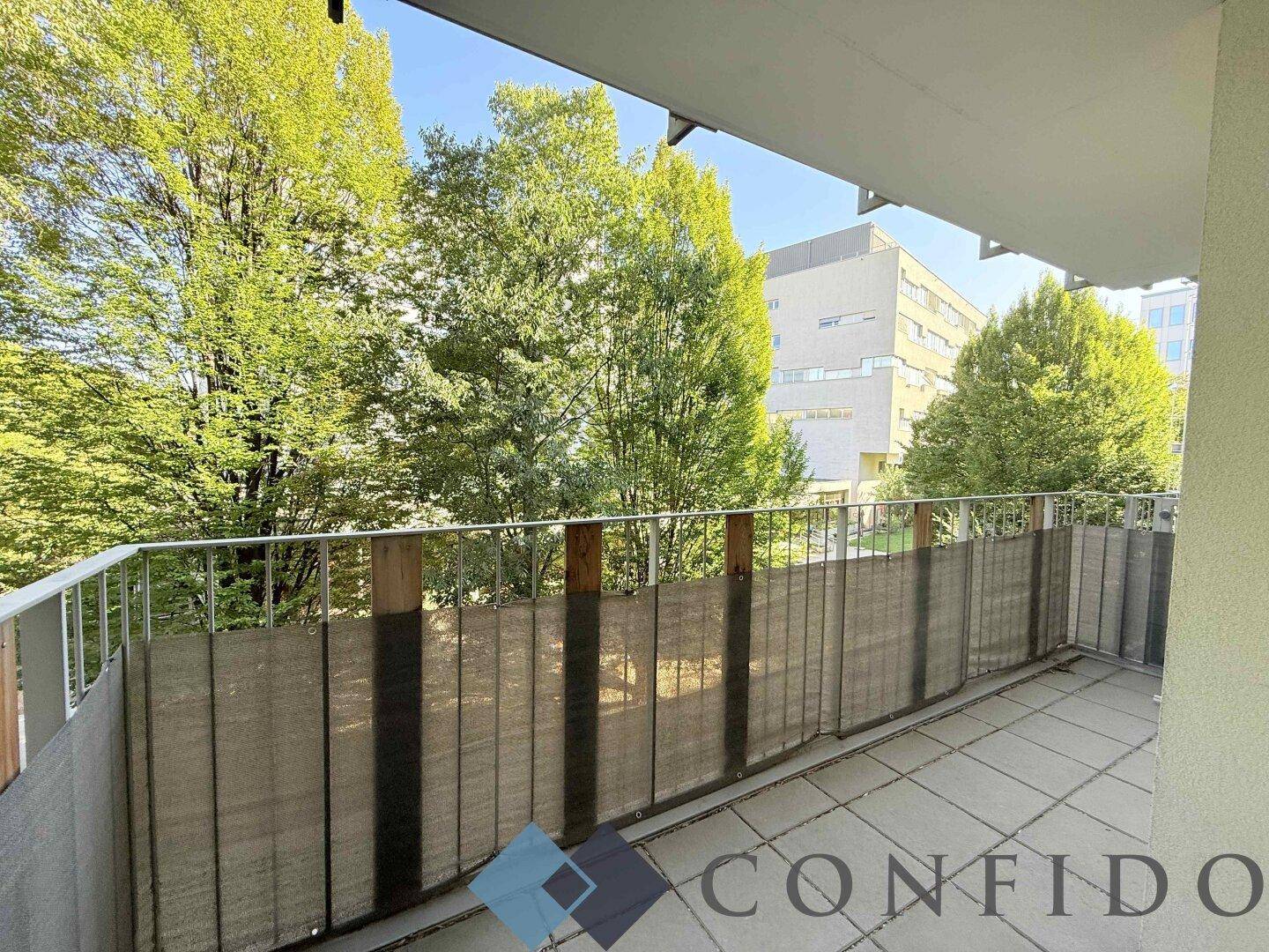 Balkon mit Blick auf umliegende Gebäude und viel Grün, bietet eine angenehme Außenfläche.