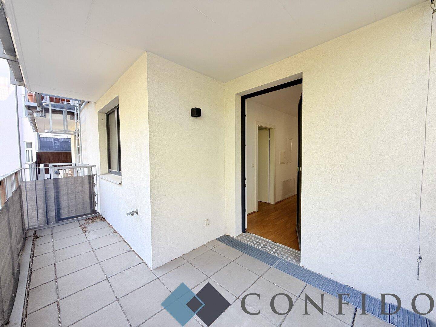 Heller Balkon mit Fliesenboden und Zugang zum Innenbereich, ideal für frische Luft.