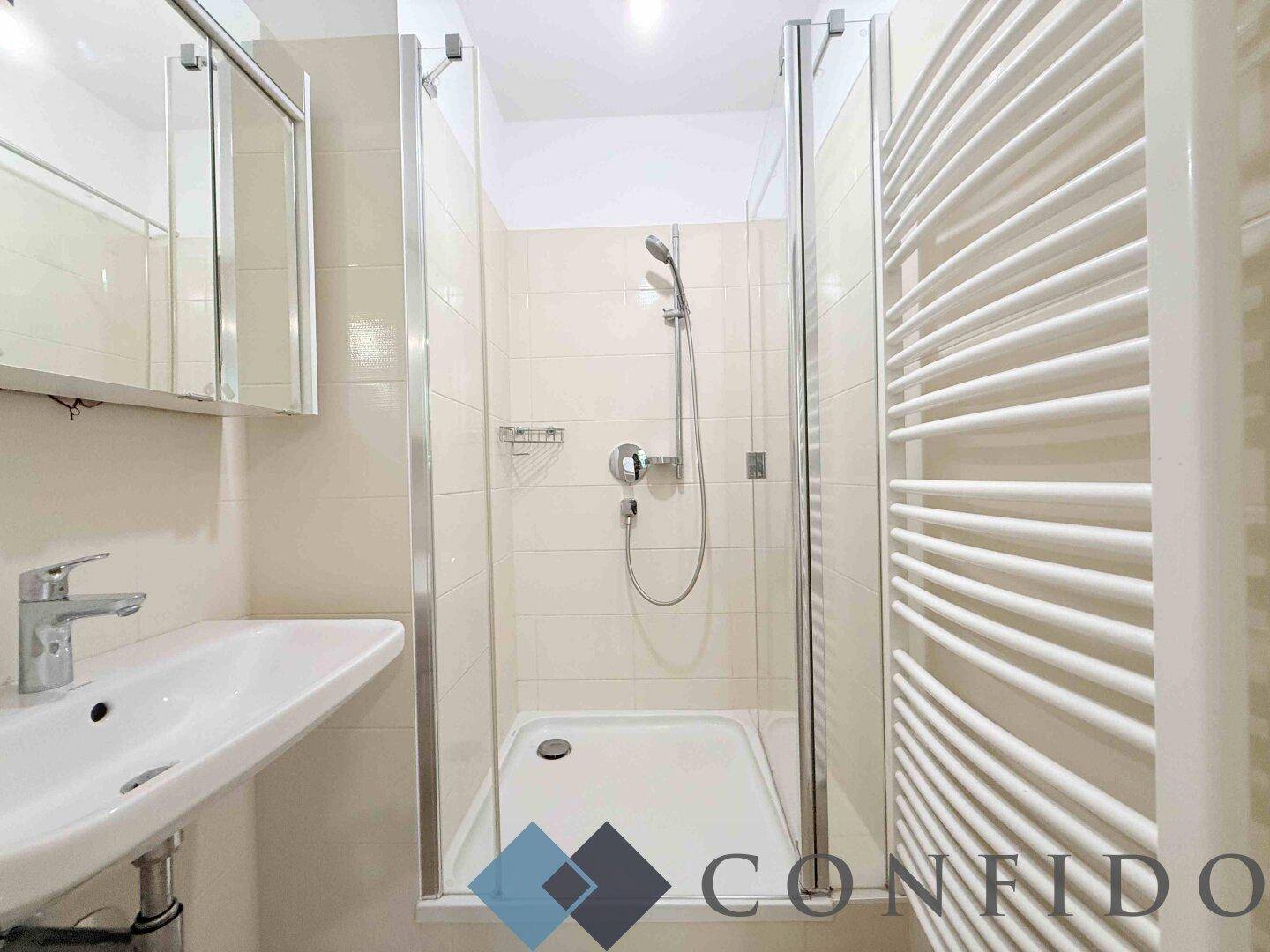 Modernes Badezimmer mit Duschkabine, Waschbecken und beheiztem Handtuchhalter.