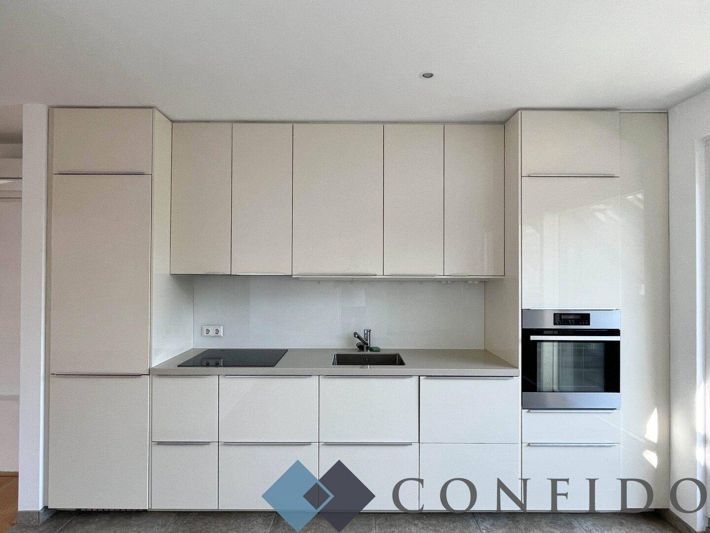 Elegante Einbauküche mit weißen Hochglanzfronten, integriertem Backofen und Induktionskochfeld.