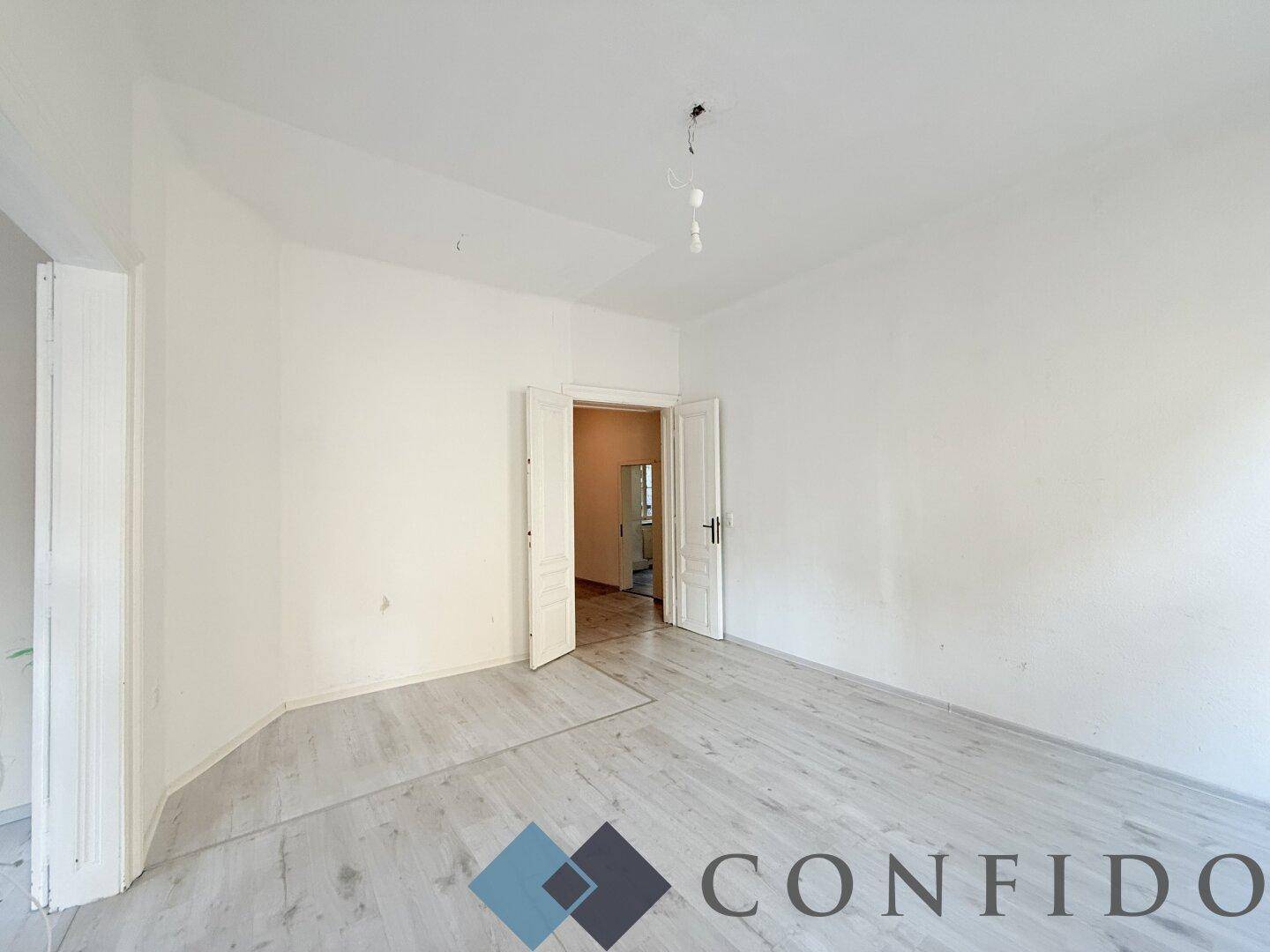 Geräumiges, leeres Zimmer mit hellem Laminatboden und weiß gestrichenen Wänden, bereit zur Gestaltung.