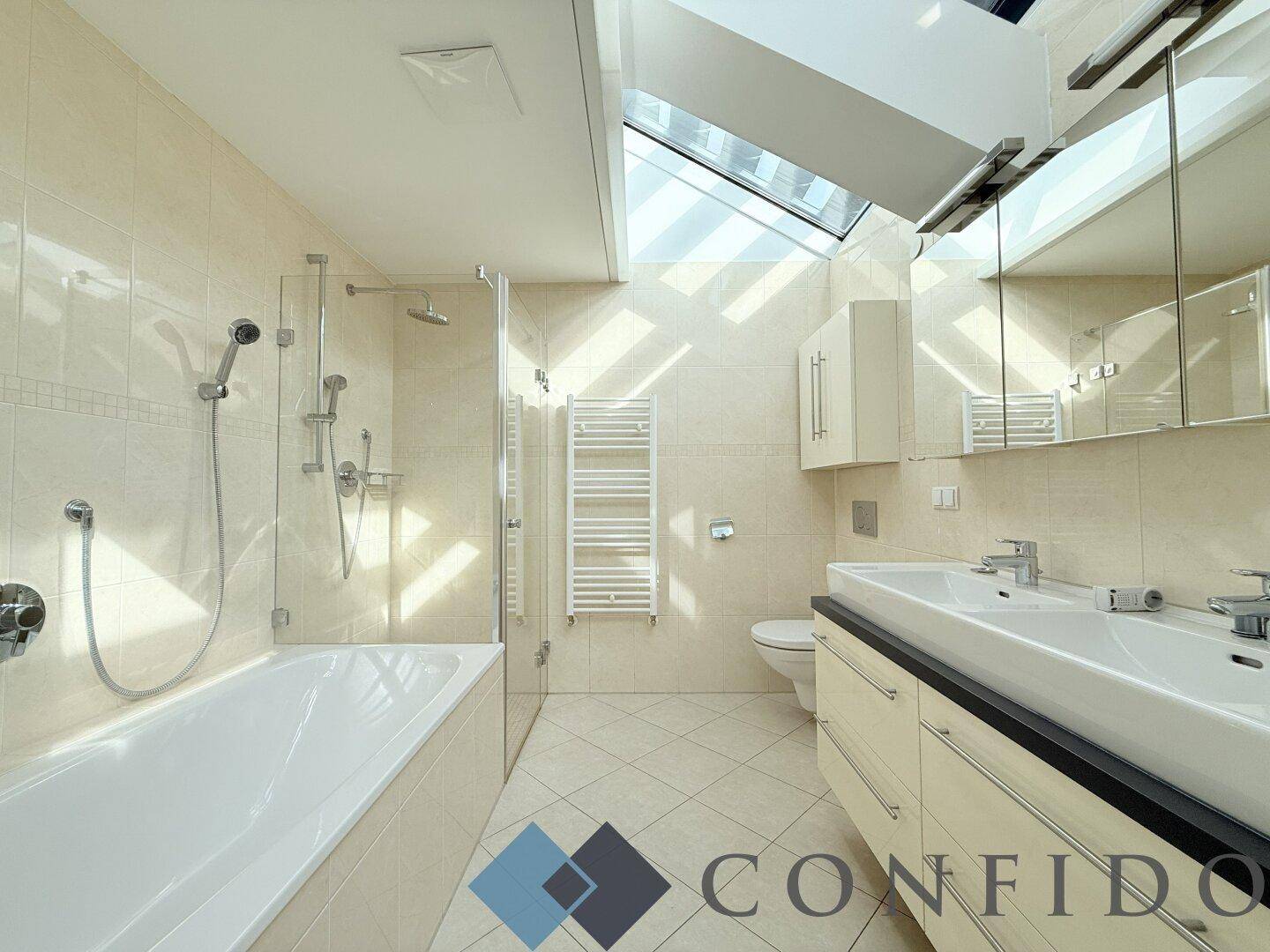 Modernes Badezimmer mit Doppelwaschbecken, Badewanne, Dusche und Dachfenster.