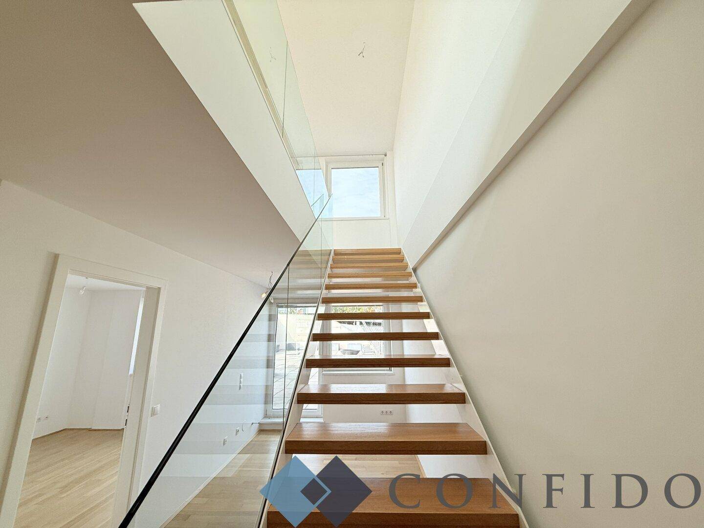 Elegante Holztreppe mit Glasgeländer, die verschiedene Ebenen des Hauses verbindet.