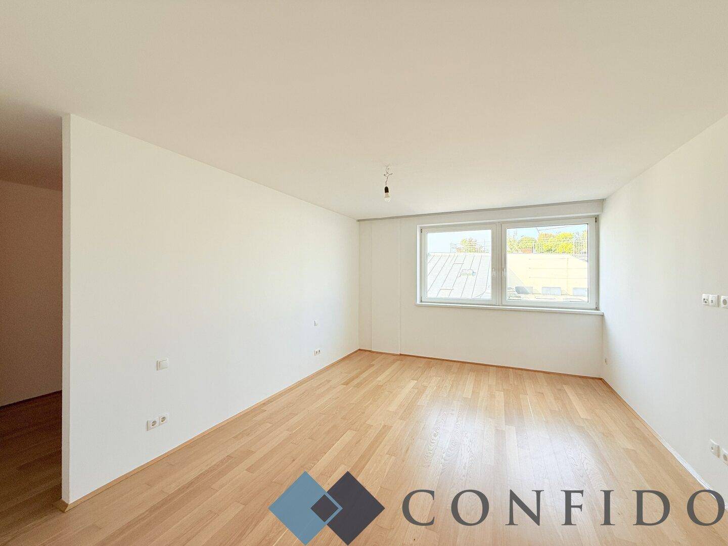 Helles, leeres Zimmer mit Parkettboden und Fenster, bereit zur individuellen Gestaltung.