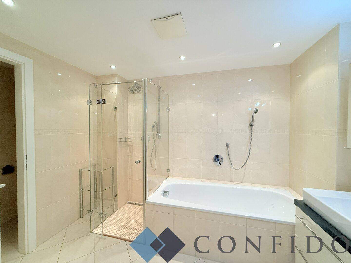 Modernes Badezimmer mit Badewanne, Duschkabine und hellen Fliesen.