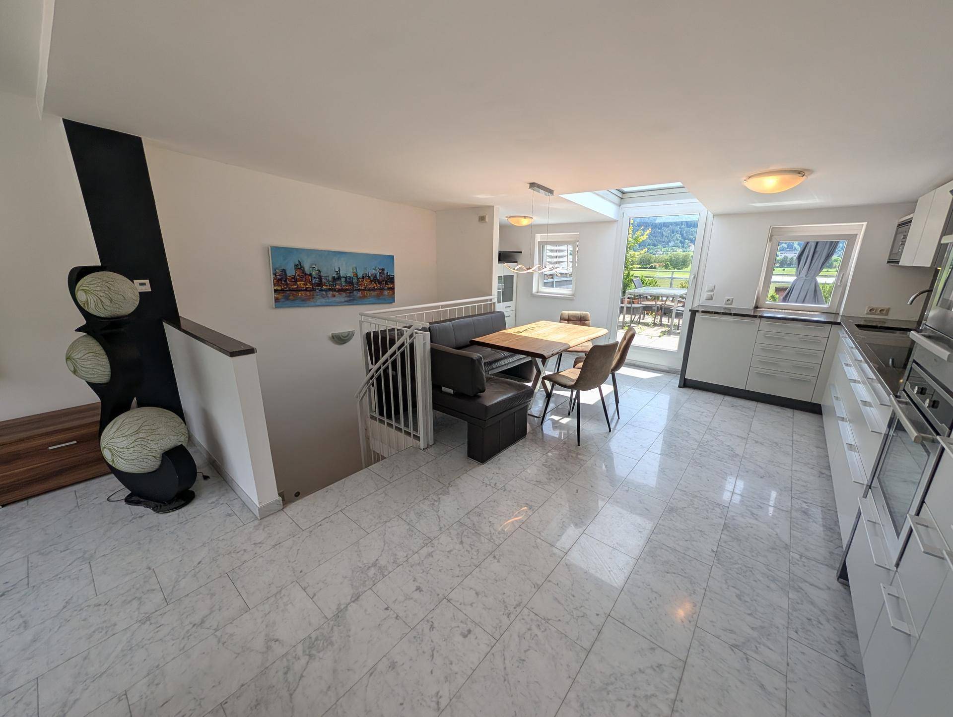 Offener Wohnbereich mit Essplatz, integrierter Küche und Zugang zur Terrasse mit Bergblick.