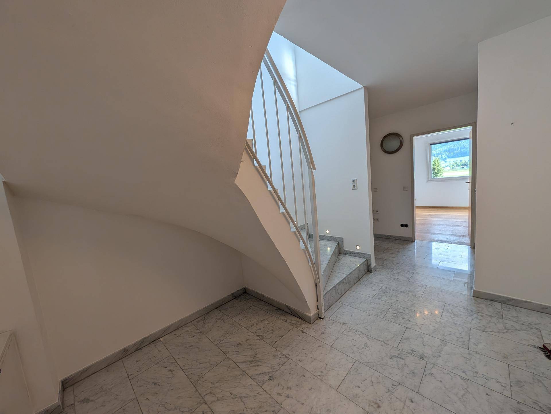 Heller Flur mit Marmorboden und Treppe, die zu den oberen Wohnbereichen führt.