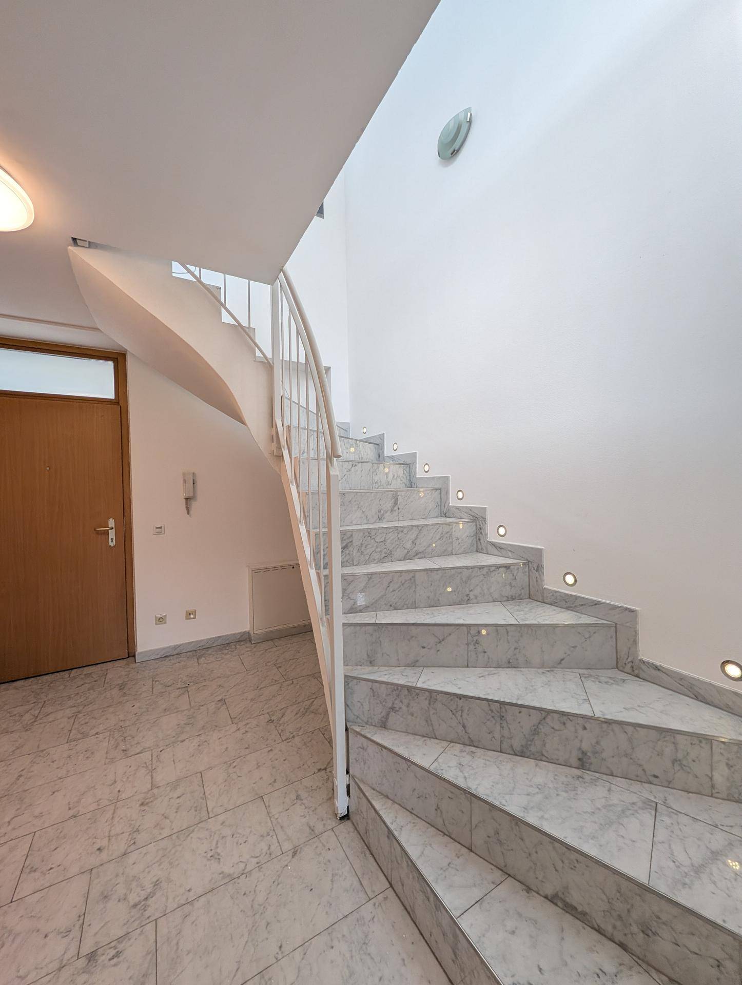 Eingangsbereich mit eleganter Marmortreppe und weißem Geländer, führt in die obere Etage.