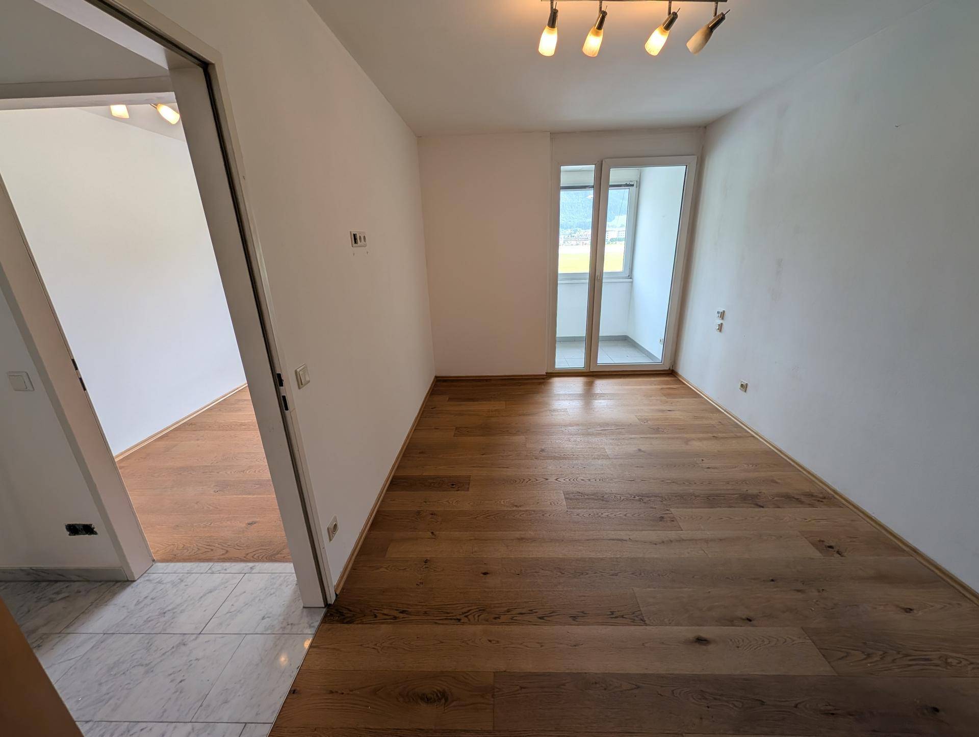 Helles Schlafzimmer mit Holzboden und Zugang zu einem französischen Balkon oder kleiner Loggia.