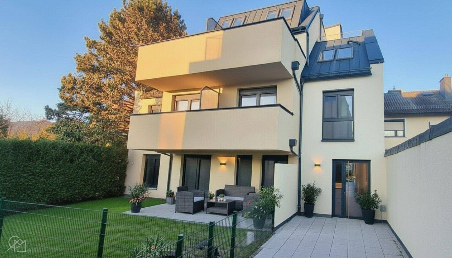 Moderne Wohnanlage mit möblierter Terrasse und gepflegtem Gartenbereich im Erdgeschoss.