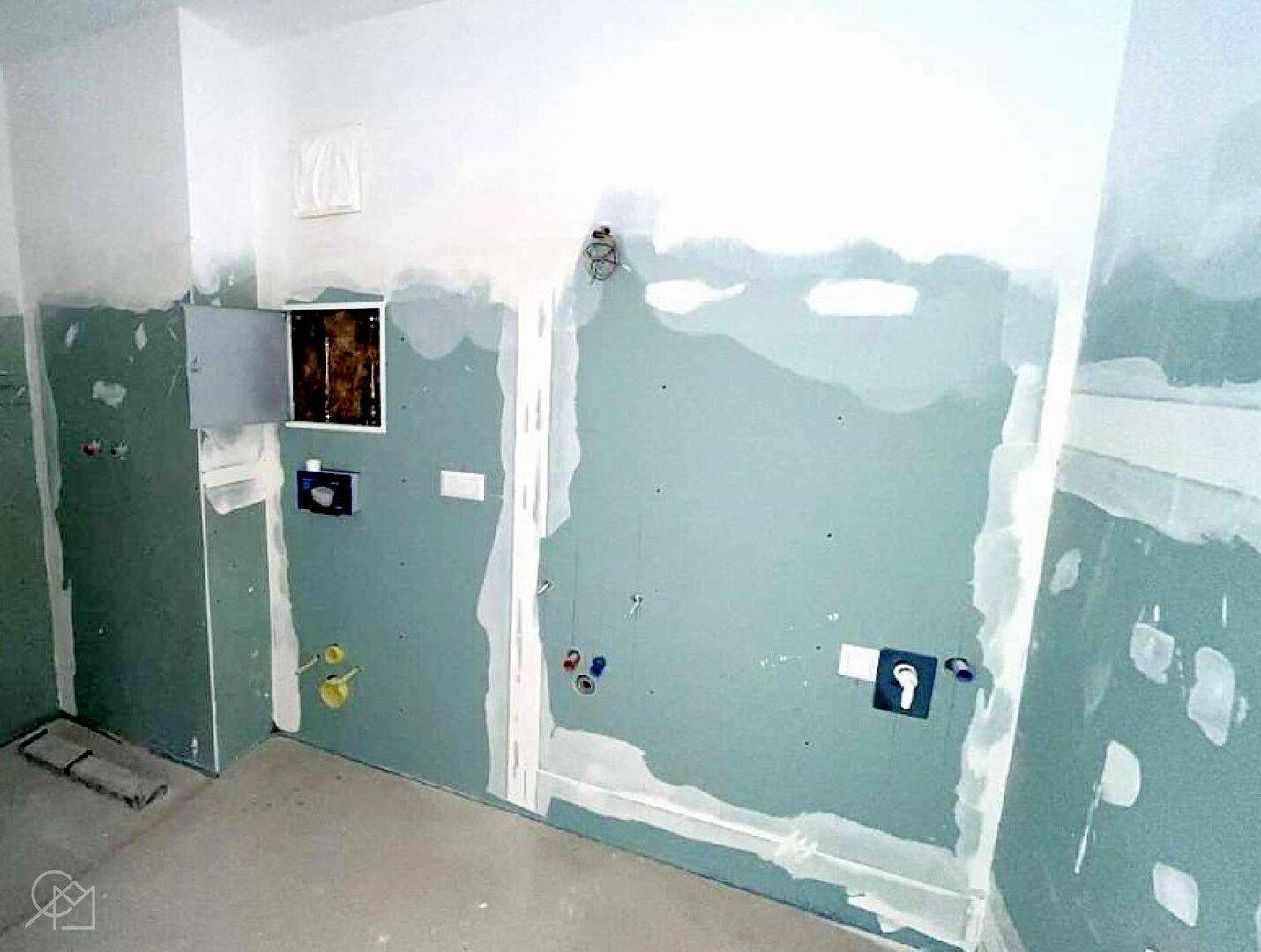 Badezimmer im Rohbau mit Trockenbauwänden und vorbereiteten Anschlüssen.