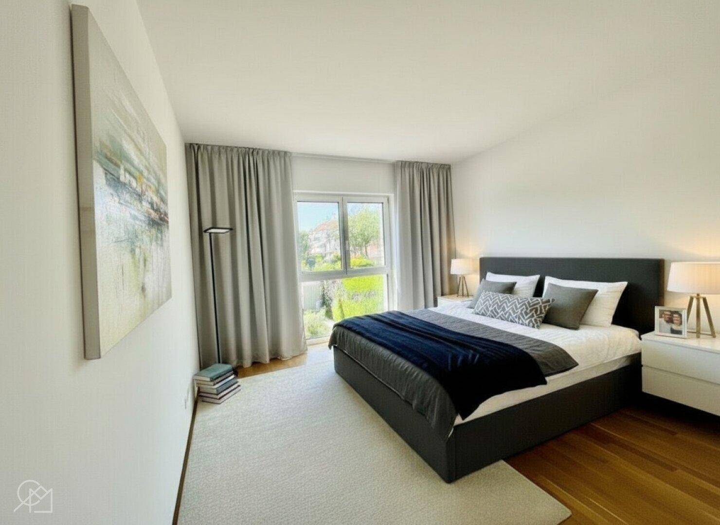 Gemütliches Schlafzimmer mit Doppelbett, Holzboden und großem Fenster mit Vorhängen.