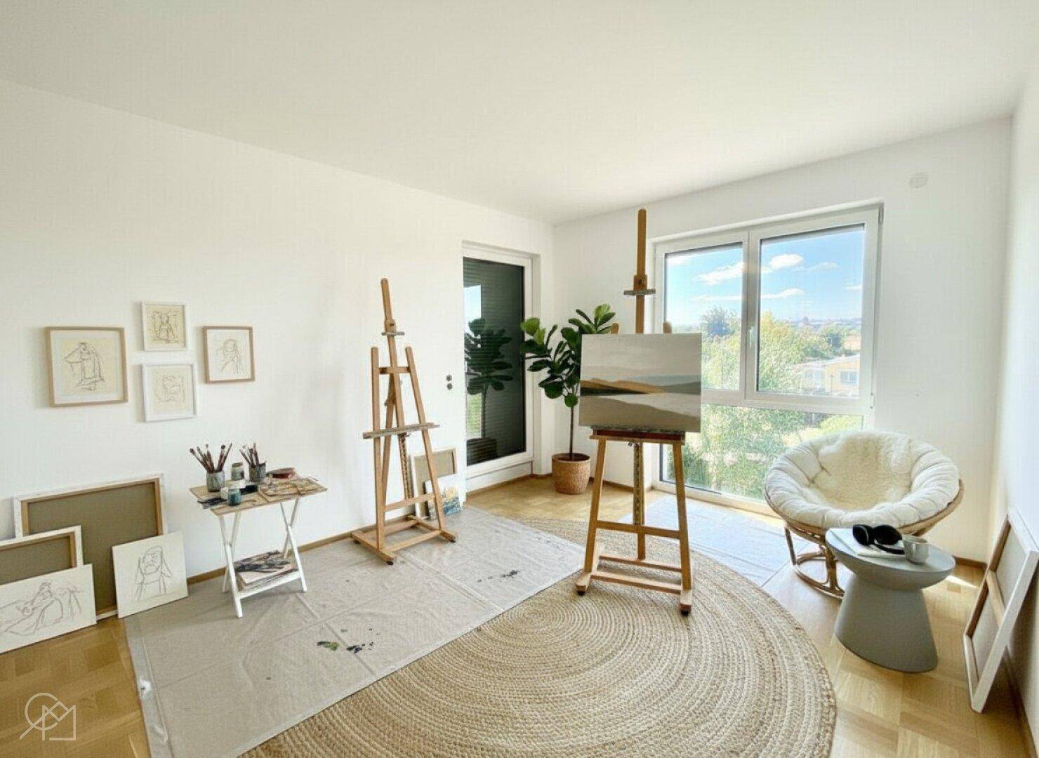 Künstleratelier mit viel Tageslicht, Holzboden und Zugang zu einem Balkon.