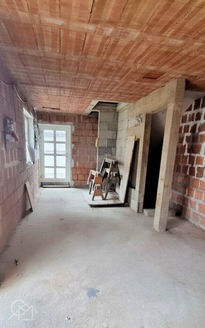 Rohbau eines Zimmers mit Ziegelwänden und Tür.