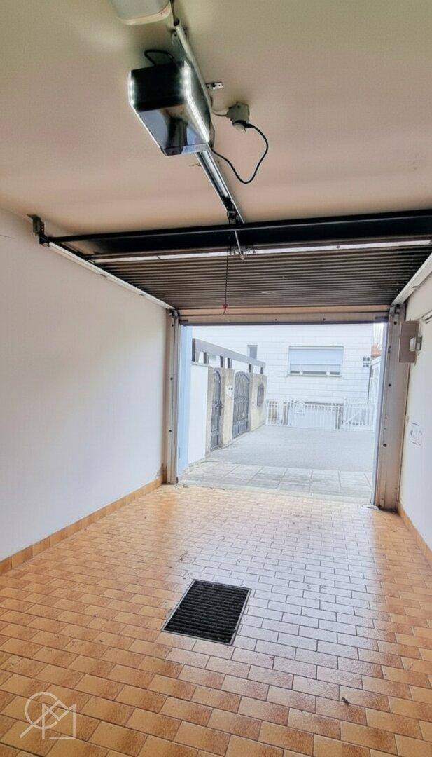 Garage mit Fliesenboden und automatischem Toröffner.