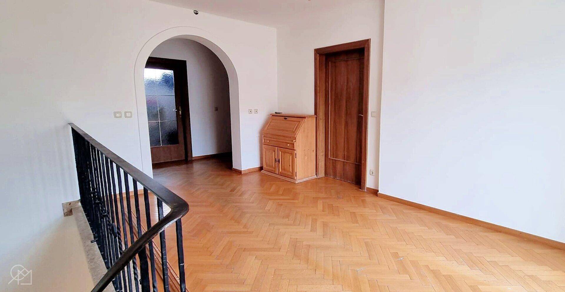 Heller Treppenabsatz mit Parkettboden und Holztüren.