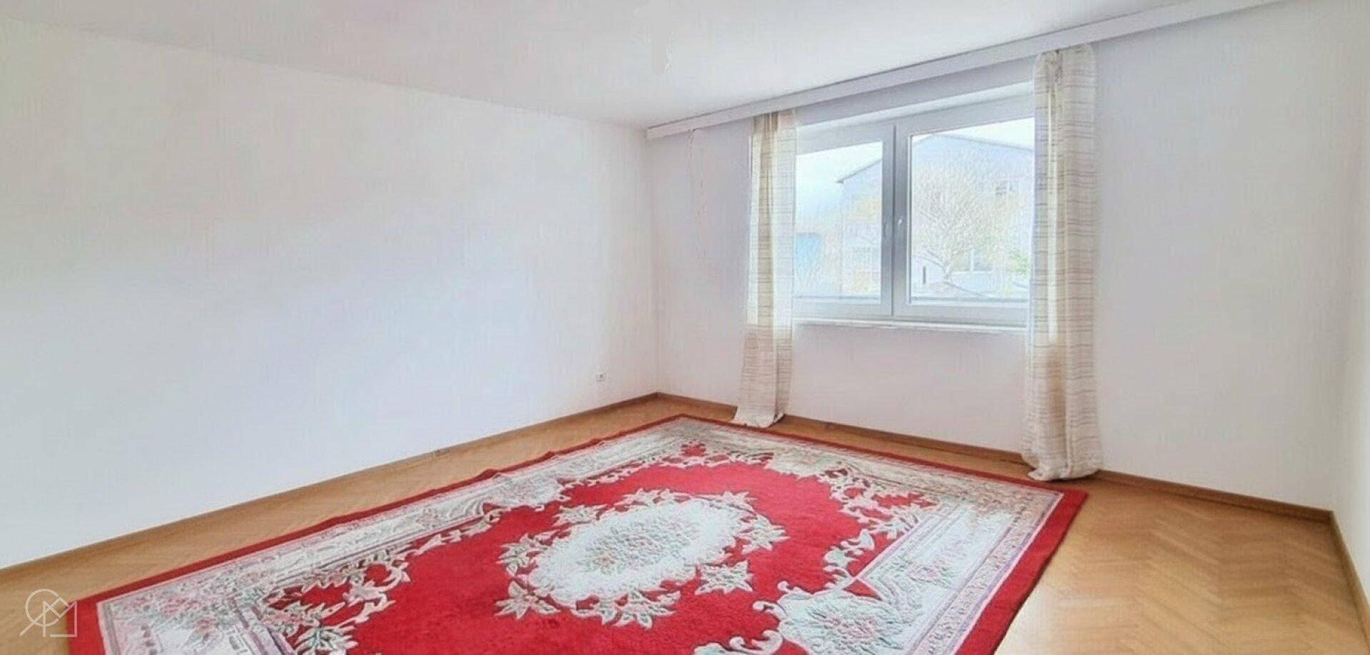 Unmöbliertes Schlafzimmer mit Parkettboden und großem Fenster.
