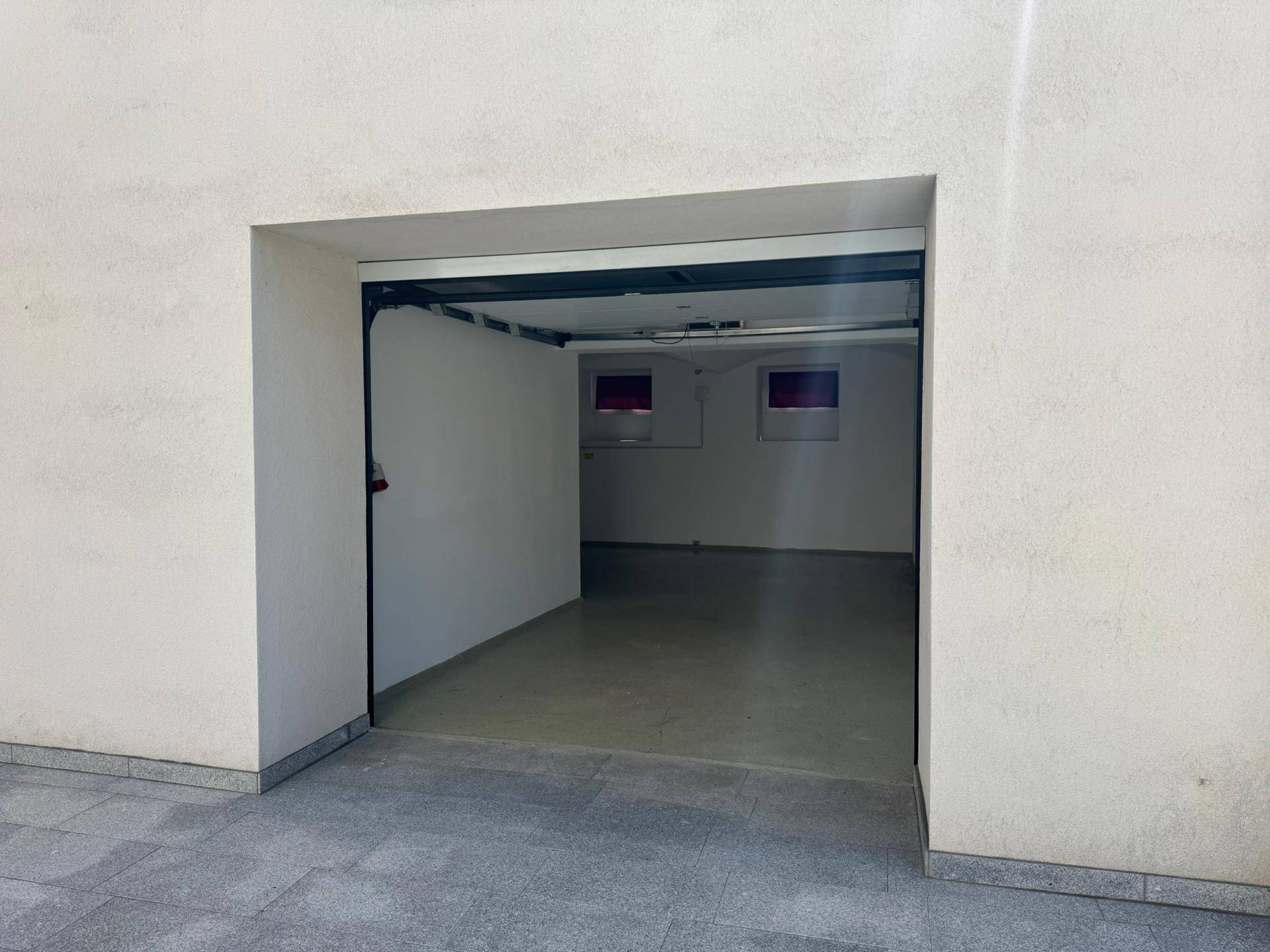 Geräumige Garage mit Rolltor und ausreichend Platz für Fahrzeuge oder Lagerung.