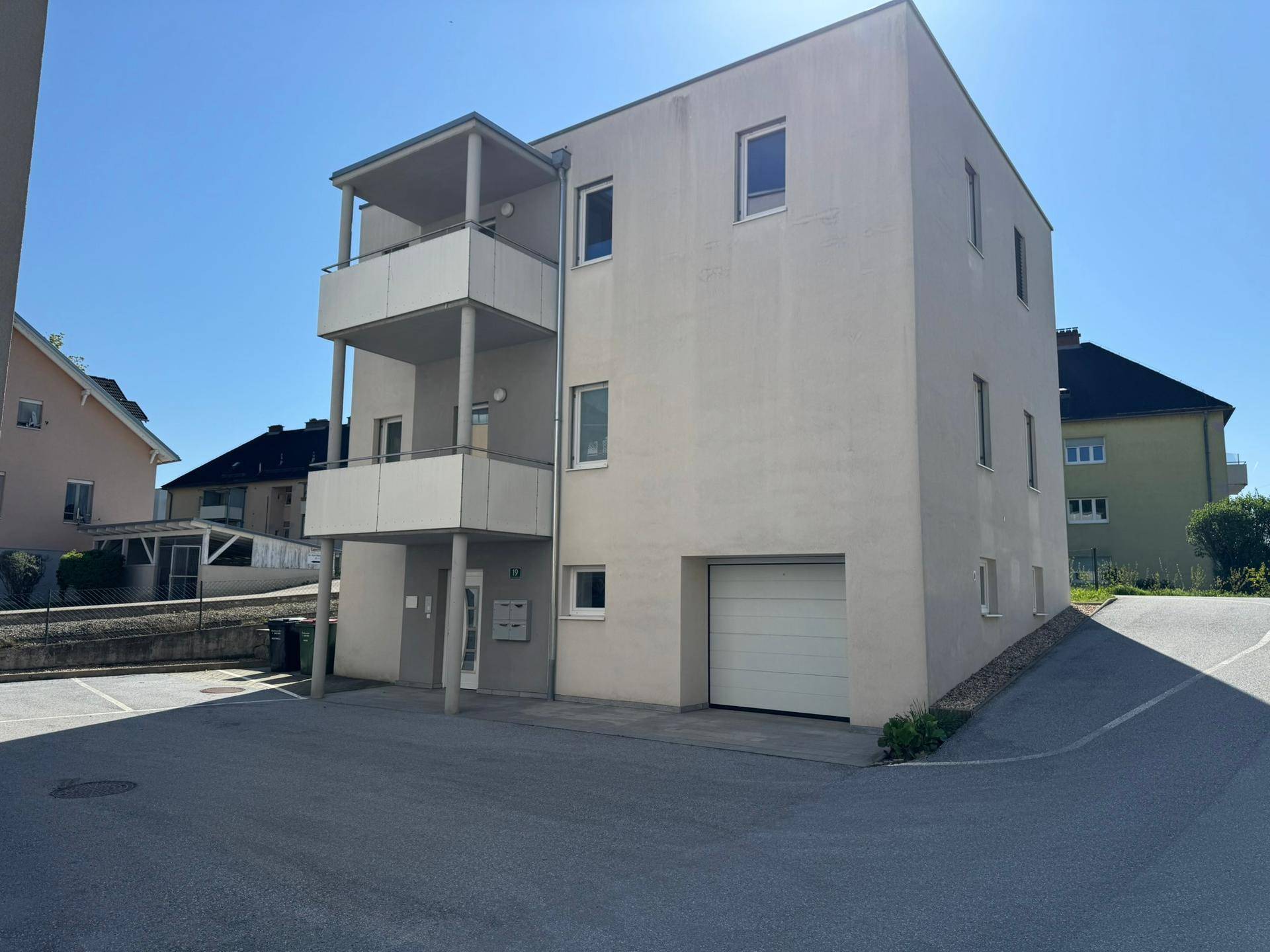Modernes Mehrfamilienhaus mit Balkonen und integrierter Garage, in sonniger Lage.