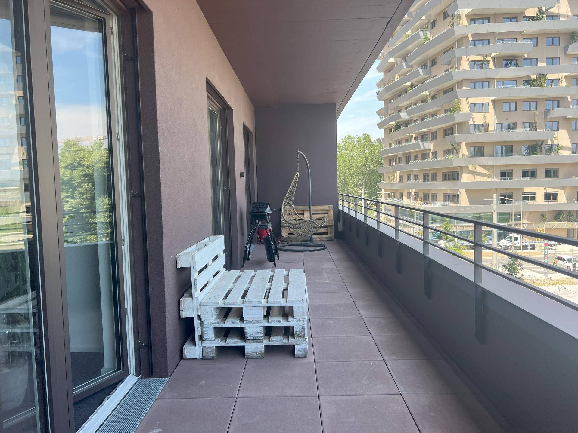 Langer Balkon mit Sitzgelegenheiten und Blick auf die umliegende Bebauung.