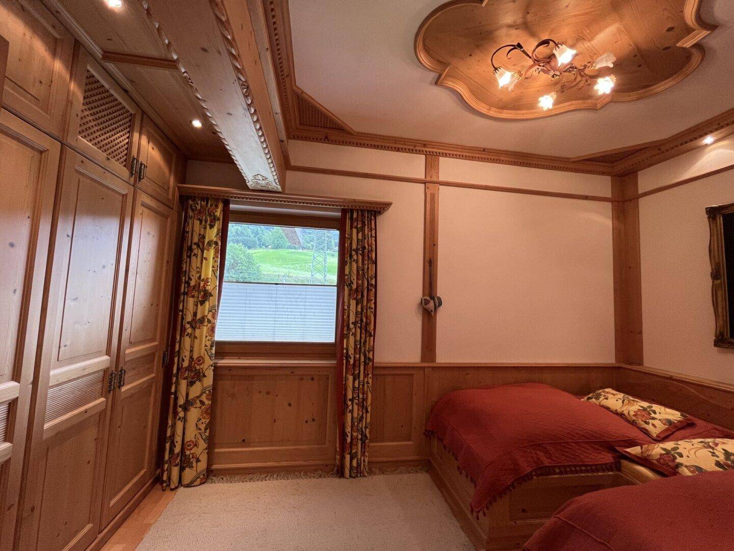 Schlafzimmer im alpinen Stil mit Holzvertäfelung, Einbauschränken und zwei Einzelbetten.