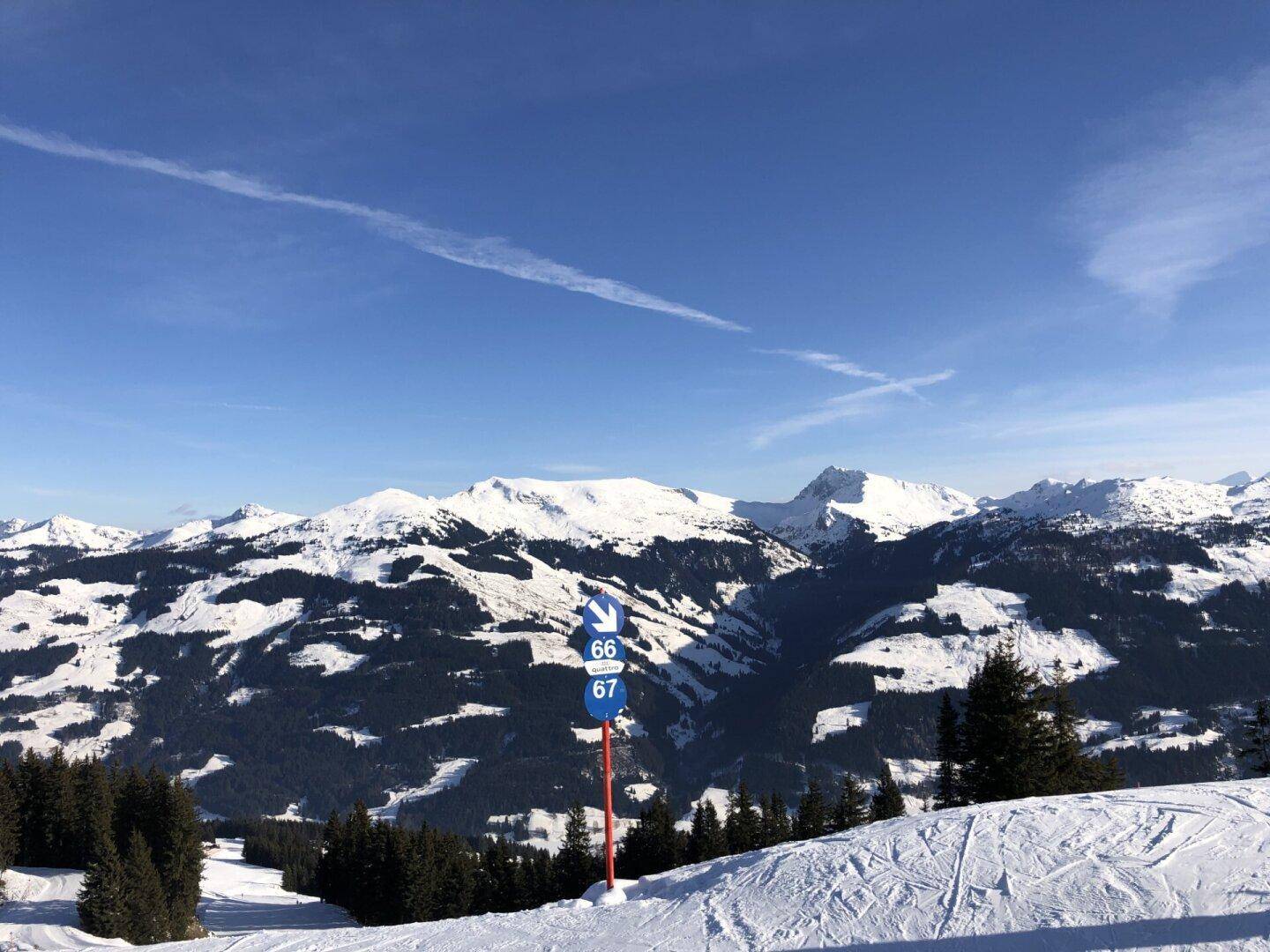 Weitläufige verschneite Berglandschaft mit Skipisten und tiefblauem Himmel.