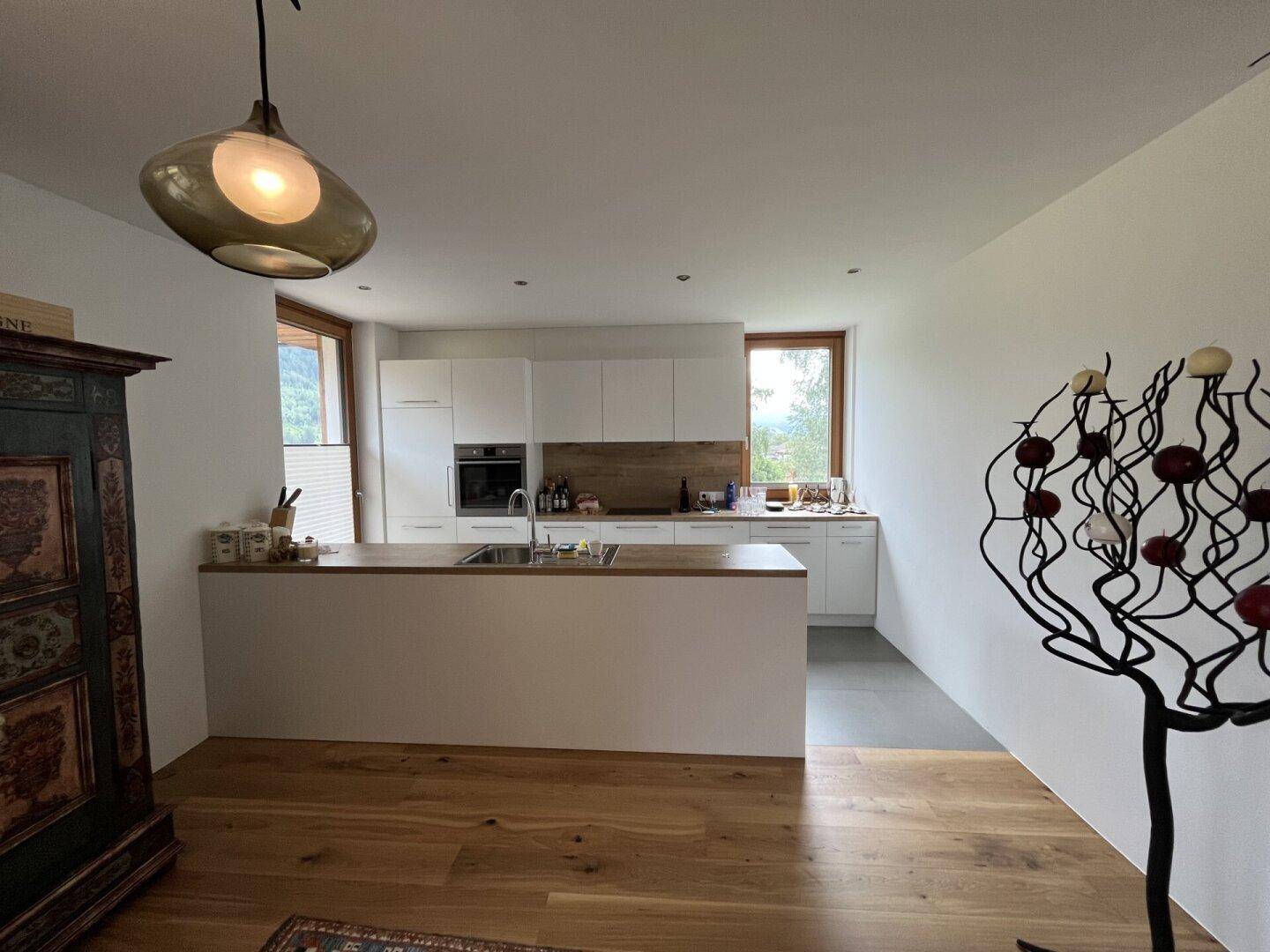 Moderne offene Küche mit weißen Schränken, Holztheke und integrierter Spüle.