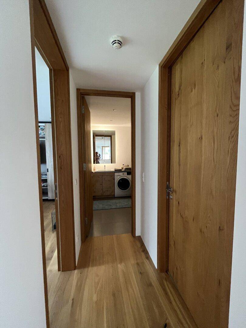 Heller Flur mit Holzboden und Holztüren, der zu weiteren Räumen führt.