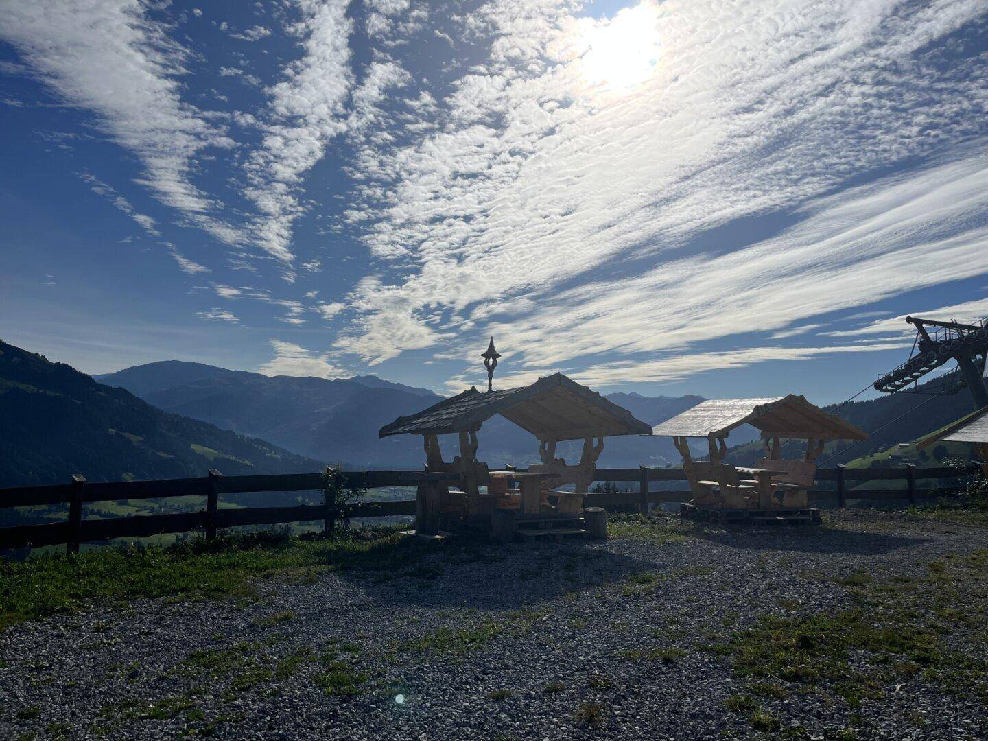 Zwei rustikale Holzpavillons mit Blick auf die umliegende Berglandschaft unter weitem Himmel.