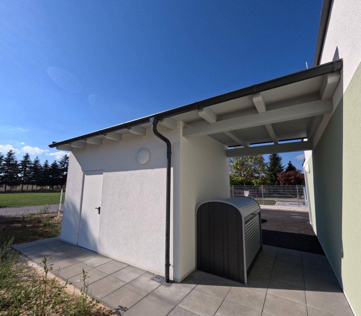 Seitenansicht eines Neubaus mit einem Abstellraum und einem überdachten Bereich, möglicherweise ein Carport.