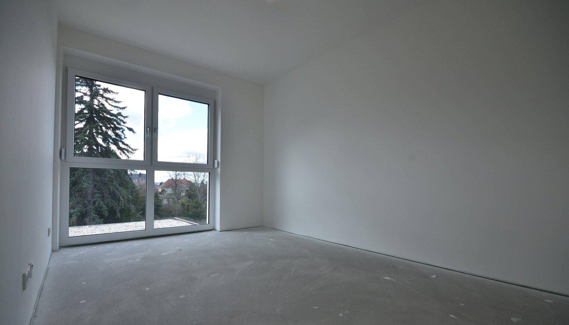 Geräumiges Schlafzimmer mit großem Fenster und Blick auf Bäume und den Gartenbereich.