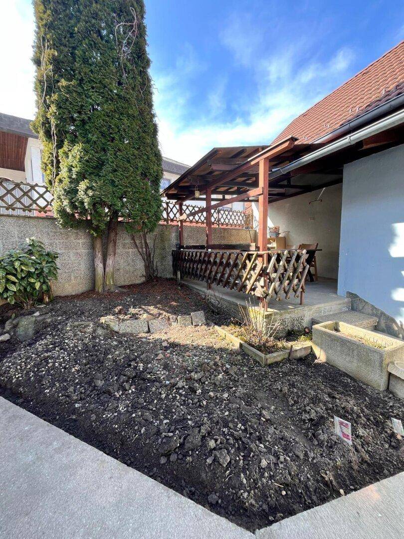 Gartenbereich mit vorbereitetem Beet und angrenzender überdachter Terrasse.