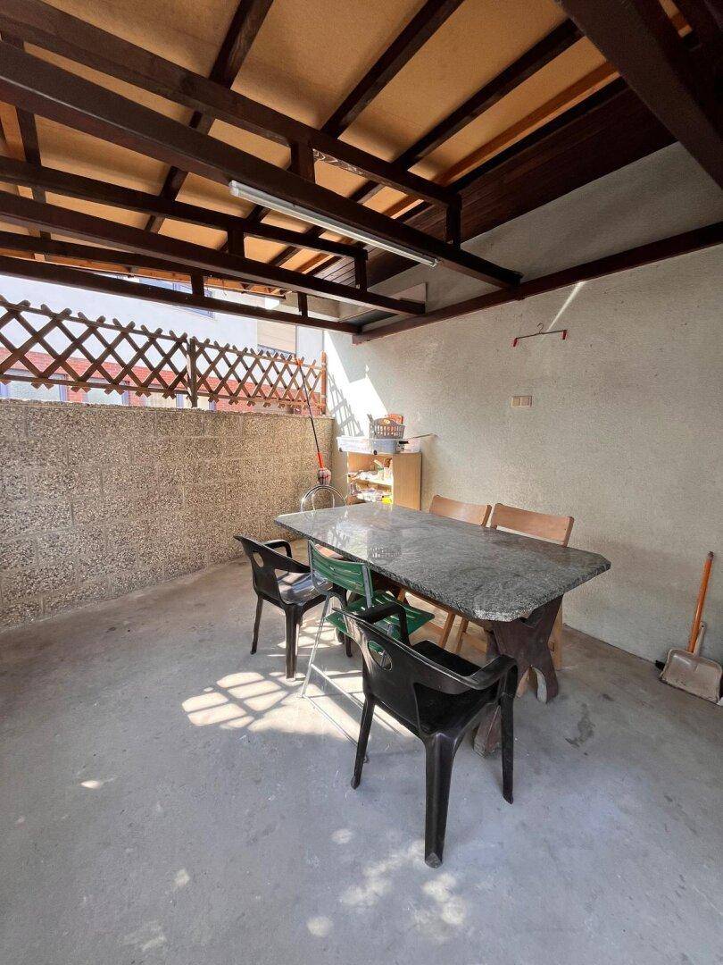Überdachte Terrasse mit Steintisch und Stühlen, ideal für entspannte Stunden im Freien.