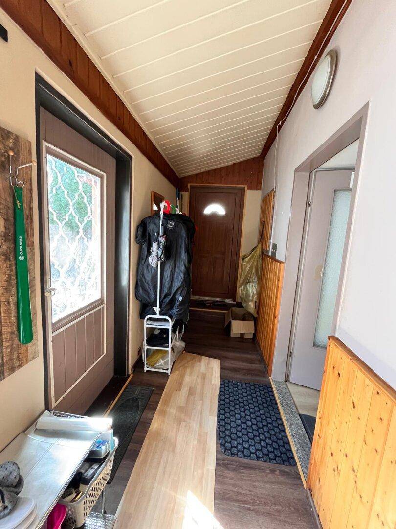 Heller Flur mit Holzpaneeldecke, Laminatboden und mehreren Türen.
