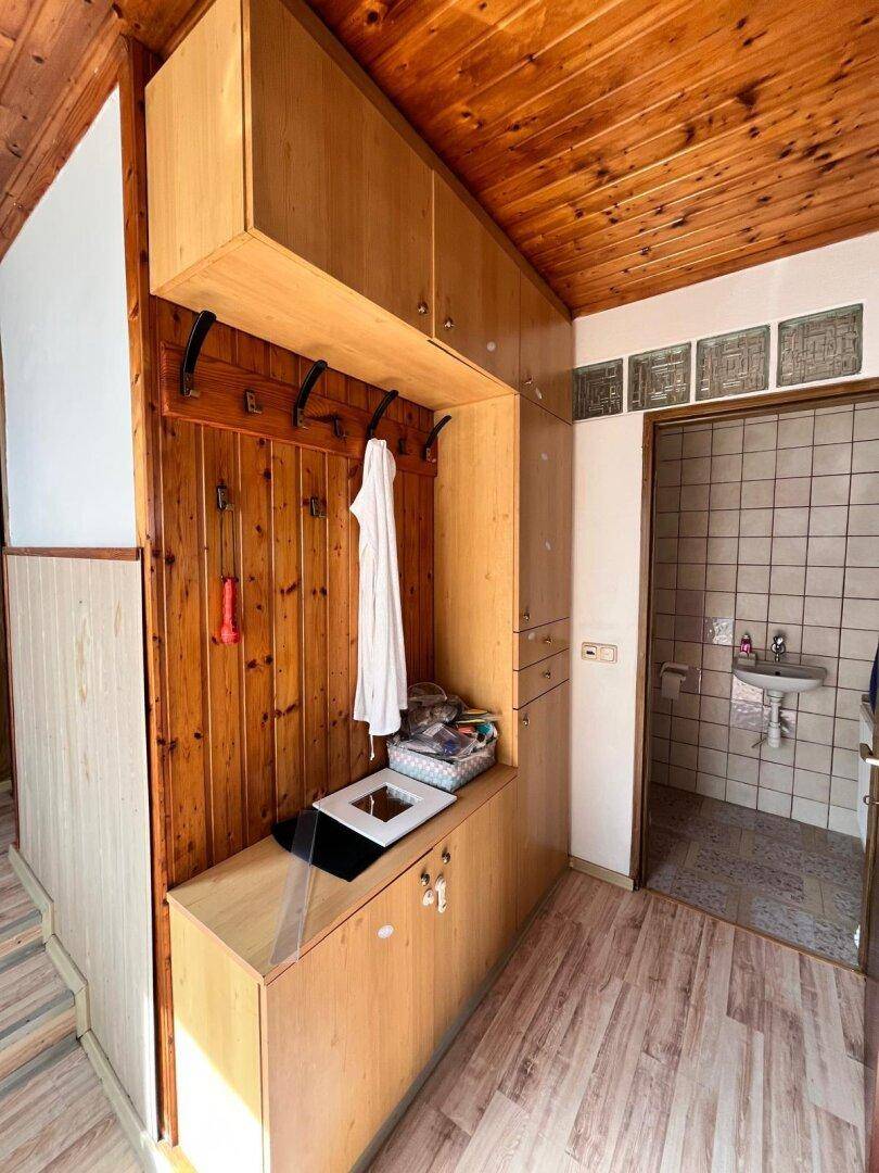 Eingangsbereich mit Holzverkleidung, eingebauten Garderobenschränken und Zugang zum WC.