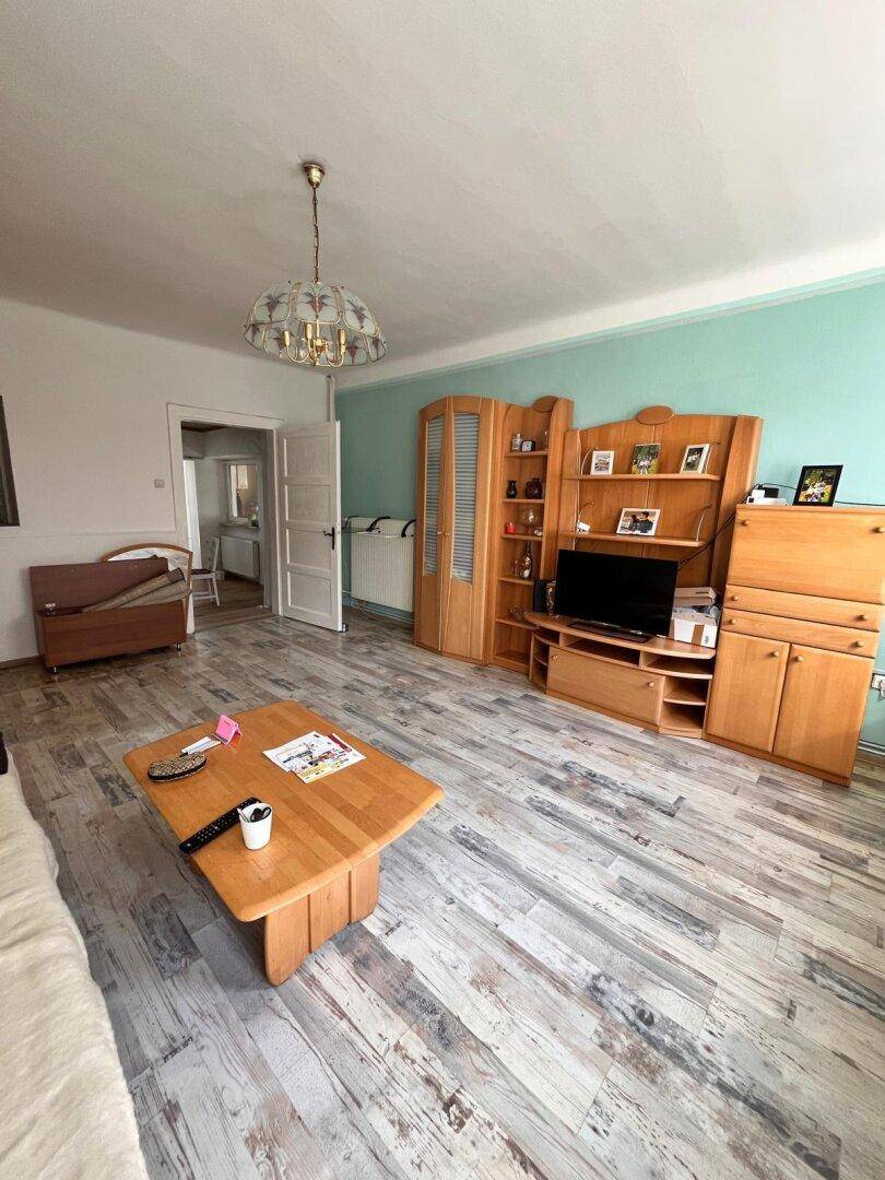Geräumiges Wohnzimmer mit Laminatboden, Holzmöbeln und einem Blick in den Flur.
