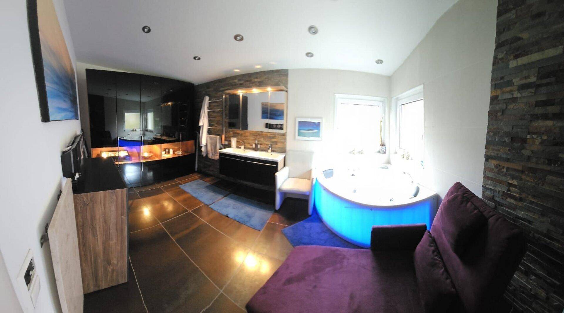 Luxuriöses Badezimmer mit Whirlpool, Fliesenboden und Steinwandakzenten.