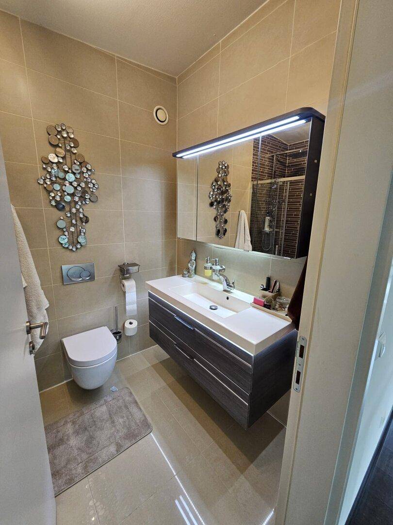 Modernes Badezimmer mit schwebendem Waschtisch, Wand-WC und Spiegelschrank.