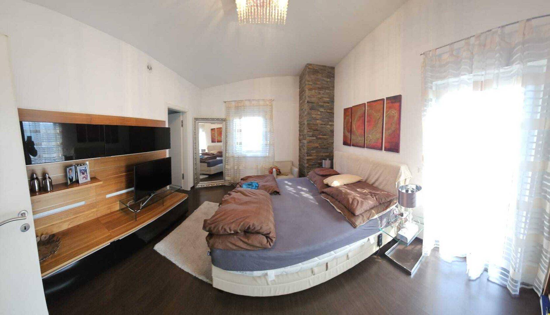 Helles Schlafzimmer mit Holzboden, Steinwandakzent und Zugang zum Balkon.