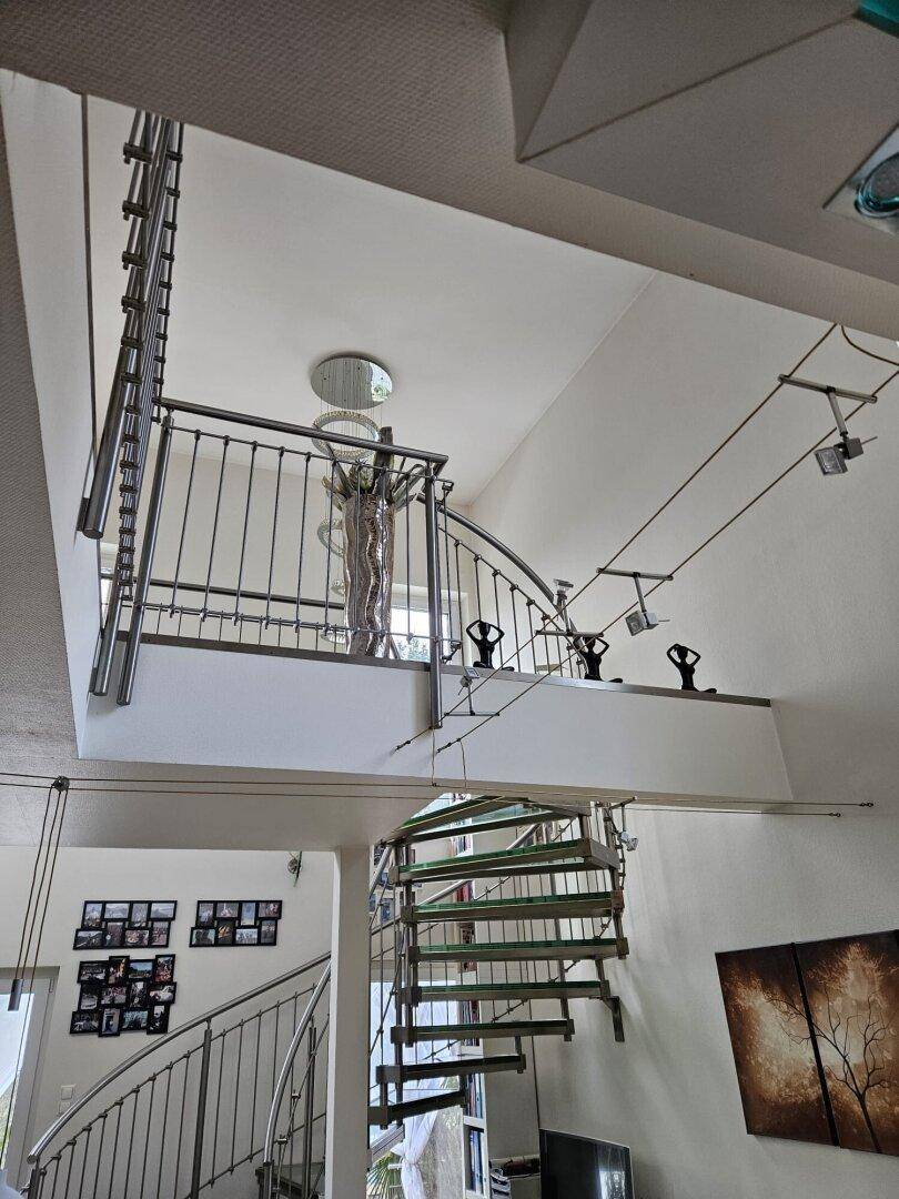 Offener Treppenbereich mit Wendeltreppe und Blick auf die darunterliegenden Etagen.