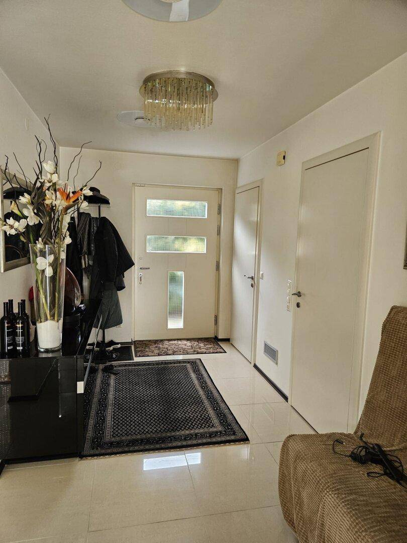 Heller Eingangsbereich mit Fliesenboden, Garderobe und moderner Beleuchtung.