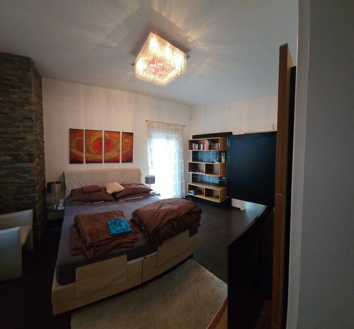 Gemütliches Schlafzimmer mit dunklem Holzboden, großem Bett und dekorativer Wandgestaltung.